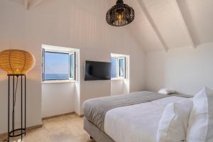 a bedroom with a bed and a flat screen tv at Escarpa - The Madeira Hideaway in Ponta do Sol