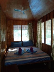 a bedroom with a bed in a room with windows at Happy Bear Moalboal Traditional Hut in Moalboal