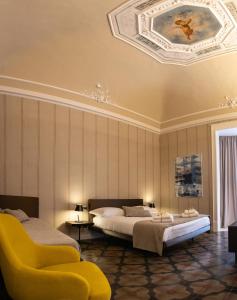 een slaapkamer met 2 bedden en een gele stoel bij B&B Palazzo Perrotta in Catania