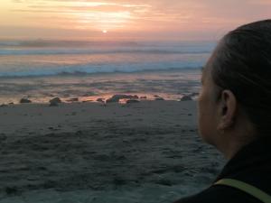 ワンチャコにあるPunta Huanchaco Hostelの夕日を眺めながら浜辺に立つ女性