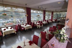 a restaurant with tables and red chairs and windows at Hotel Lahnblick in Bad Laasphe
