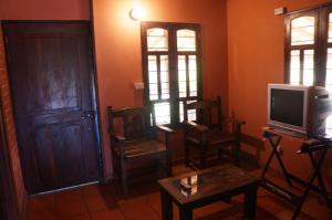 a living room with a tv and chairs and a door at Hospedaje Rural Misia Emilia in Medellín