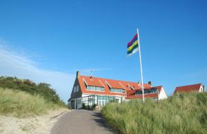 
a house on the side of a road with a flag on it at Strandhotel Terschelling in Formerum

