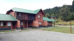 a large brick house with a green roof at Lago Puelo Departamentos Turisticos in Lago Puelo