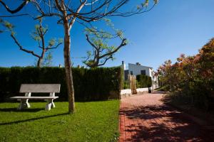 un banco del parque sentado en el césped junto a un árbol en Apartamentos Golf Place, en Borriol