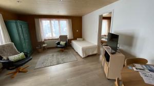 ein Wohnzimmer mit einem Bett und einem TV in einem Zimmer in der Unterkunft Chalet Acheregg in Wengen