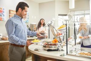 a group of people standing in a kitchen preparing food at Staybridge Suites - Miami International Airport by IHG in Miami