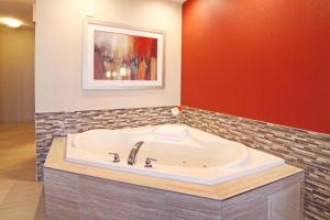 a bath tub in a room with a red wall at Holiday Inn Express and Suites Calgary University, an IHG Hotel in Calgary