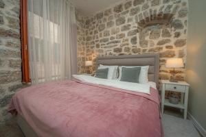 a bedroom with a bed and a stone wall at Antika Guesthouse in Kotor