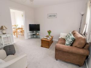 a living room with a couch and a tv at Kite Cottage in Brackley