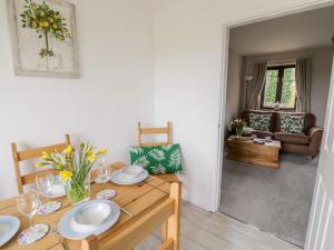 a dining room with a wooden table with plates on it at Kite Cottage in Brackley