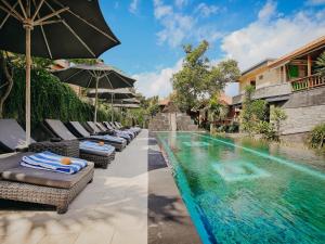 einen Pool mit Stühlen und Sonnenschirmen neben einem Resort in der Unterkunft Bale Gede Lembongan in Nusa Lembongan