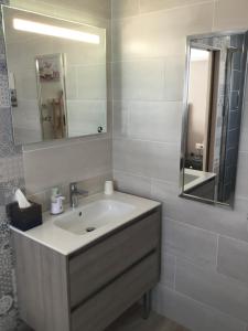 bagno bianco con lavandino e specchio di Chambre avec charme a Garons