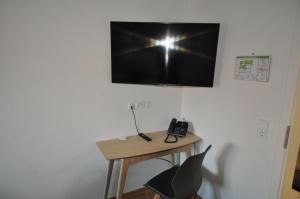 a desk with a phone and a television on a wall at D´r Rechenmacher in Michelfeld