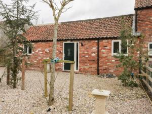 a brick house with a bird feeder in front of it at Robin's Nest Cottage in Great Driffield