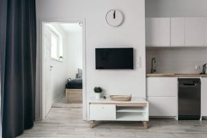a kitchen with white cabinets and a tv on a wall at Hello Apartments RAI Rajska in Gdańsk