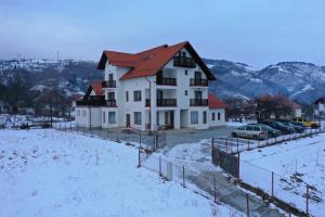 a white house with a red roof in the snow at Hotel Rabbit Bran in Moieciu de Jos