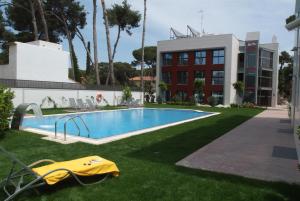 une piscine dans l'herbe à côté d'un bâtiment dans l'établissement Apartamentos Royal Marina Gardens, à Castelldefels