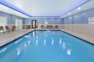 a pool in a hotel with chairs and tables at Holiday Inn Express & Suites - Painesville - Concord by IHG in Painesville