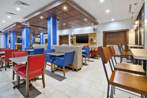 a restaurant with tables and chairs and a tv at Holiday Inn Express & Suites - Painesville - Concord, an IHG Hotel in Painesville