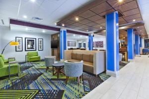PainesvilleにあるHoliday Inn Express & Suites - Painesville - Concord, an IHG Hotelの青い柱と椅子とテーブルが備わるロビー