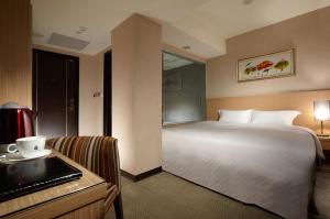 a hotel room with a bed and a desk with a desk at The Metro Hotel Taichung in Taichung