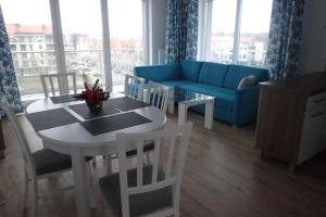 ein Wohnzimmer mit einem Tisch und einem blauen Sofa in der Unterkunft Ekskluzywny apartamet Pan Tadeusz III z widokiem na jezioro in Giżycko
