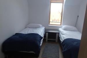 two beds in a small room with a window at Ekskluzywny apartamet Pan Tadeusz III z widokiem na jezioro in Giżycko