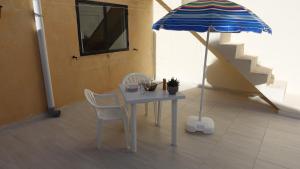 a table with chairs and an umbrella in a room at Mamina's House in il-Baħrija