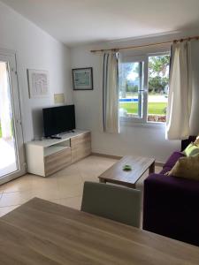 Una sala de estar con televisión y un sofá. en Solmar menorcacom apartamento 2 dormitorios, en Cala'n Bosch