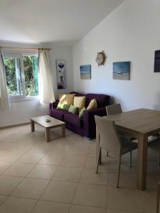 Una sala de estar con un sofá morado y una mesa. en Solmar menorcacom apartamento 2 dormitorios, en Cala'n Bosch