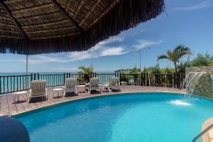 a swimming pool with chairs and a view of the ocean at Residence Vespucci Flat Beira Mar in Natal