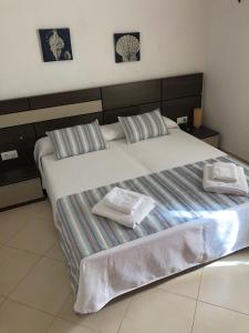 Un dormitorio con una cama grande con dos toallas encima. en Solmar menorcacom apartamento 2 dormitorios, en Cala'n Bosch 36 fotos más