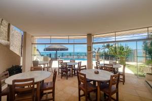 un restaurante con mesas y sillas y vistas al océano en Residence Vespucci Flat Beira Mar en Natal