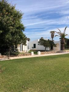 a white building with trees and a grass field at Solmar Menorcacom in Cala en Bosc