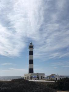 a lighthouse sitting on top of a hill next to the ocean at Solmar Menorcacom in Cala en Bosc