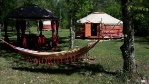 a hammock in a field next to a yurt at Les yourtes de Bascot in Vaylats