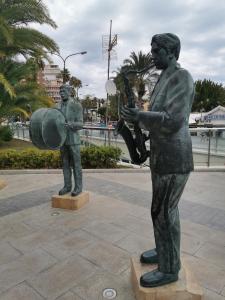 una estatua de un hombre tocando una guitarra al lado de un hombre con una guitarra en Oasis Beach juan en Guardamar del Segura