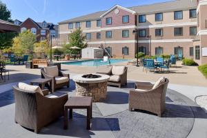 a patio with chairs and tables and a pool at Staybridge Suites O'Fallon Chesterfield by IHG in O'Fallon