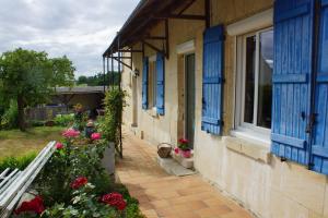 uma casa com janelas azuis e flores no quintal em La Bretonnière, Longère Picarde em Passel