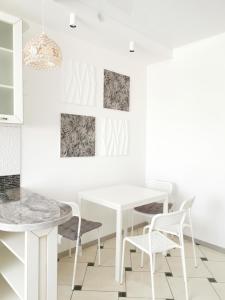 a white dining room with a white table and chairs at Manufactura apartments 2 in Sumy