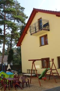 a house with a playground with chairs and a slide at Kama Apartament Pobierowo in Pobierowo