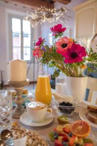 un tavolo con un vaso di fiori e un vaso di succo d'arancia di La Maison B&B a Lugo