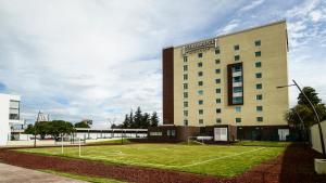 un bâtiment d'hôtel avec une pelouse devant lui dans l'établissement Staybridge Suites Puebla, an IHG Hotel, à Puebla