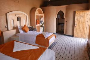 sypialnia z 2 łóżkami w pokoju z drzwiami w obiekcie Maison bedouin Merzouga w mieście Merzouga