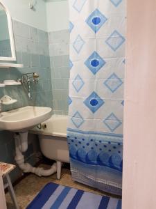 een badkamer met een wastafel, een bad en een douchegordijn bij Уютная квартира посуточно улица Белова in Chernihiv