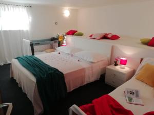 a bedroom with two beds and a window with a pink candle at Apartments Berovic Kaprije in Kaprije