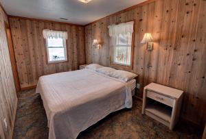 a bedroom with a bed and a window and wooden walls at Outer Banks Motel in Buxton