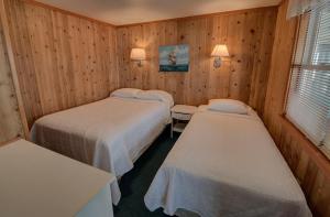 two beds in a room with wooden walls at Outer Banks Motel in Buxton