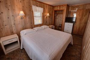 um quarto com uma cama branca e uma televisão em Outer Banks Motel em Buxton